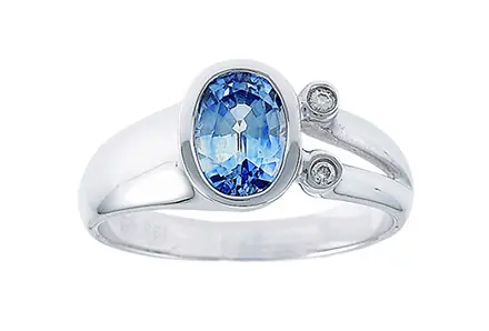 An oval blue sapphire in a white-gold bezel ring with two small round diamonds beside it